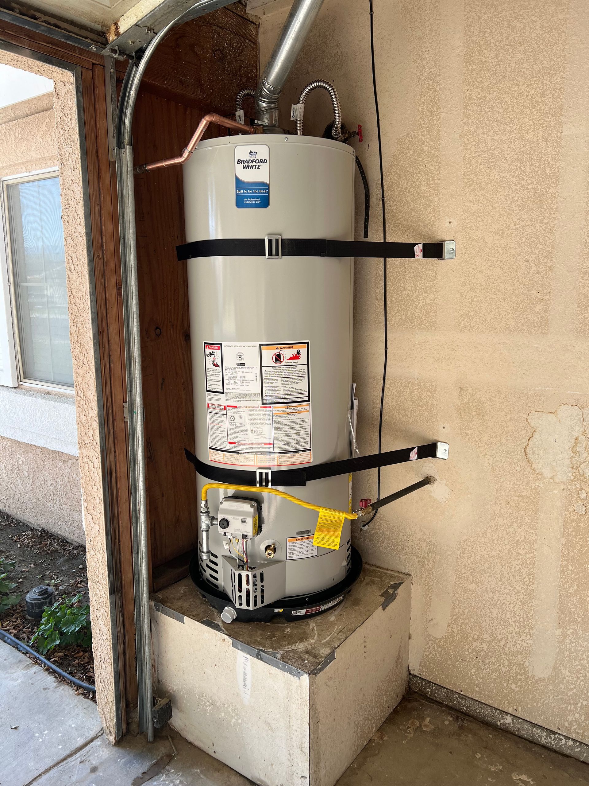 A water heater is attached to the side of a building.