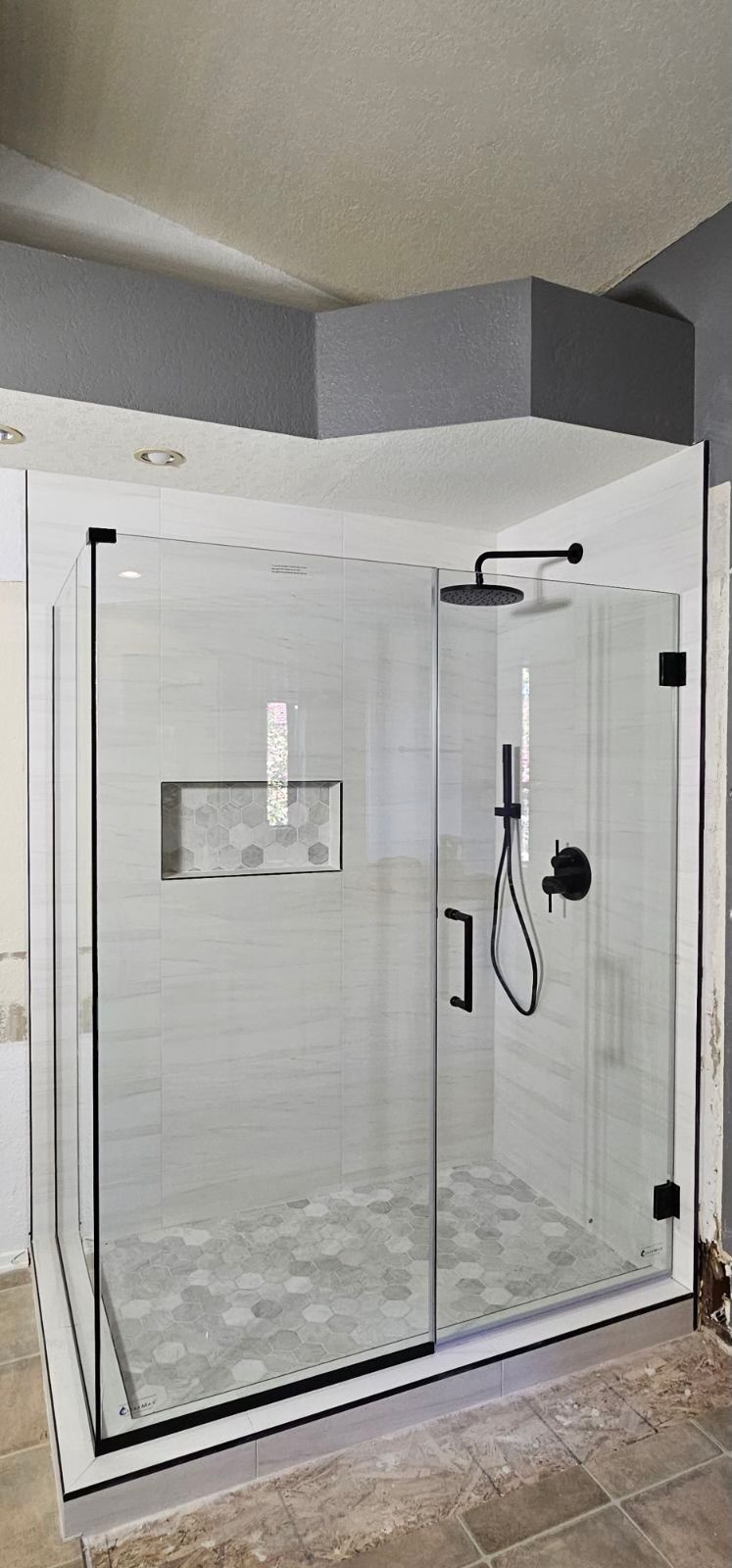 A bathroom with a walk in shower with a glass door and a shower head.