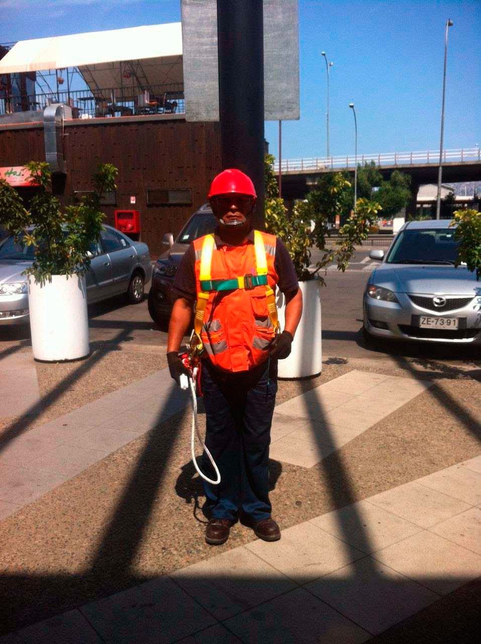 Un hombre que lleva un casco y un chaleco de seguridad está parado en un estacionamiento.