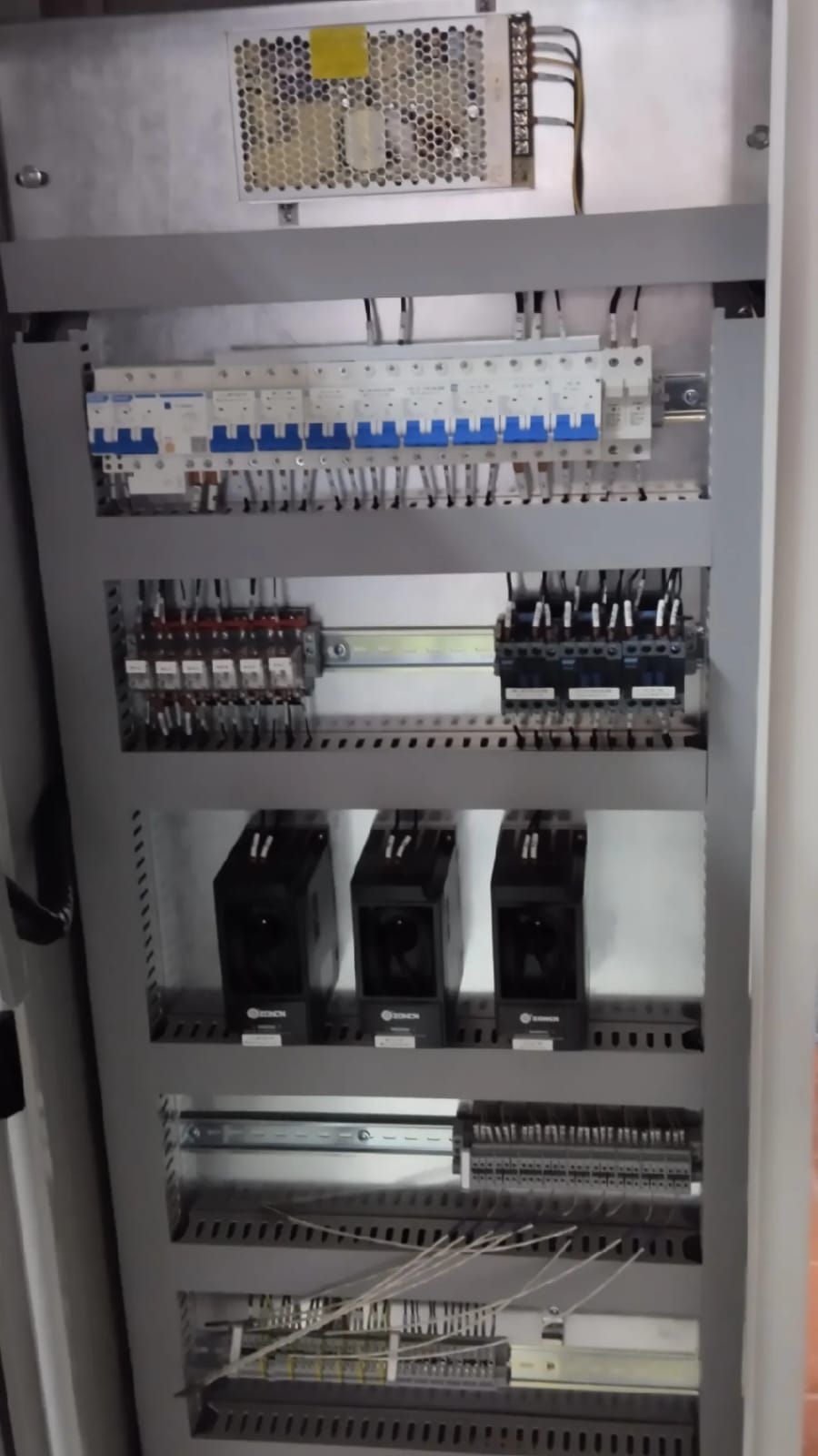 Un primer plano de un panel de control eléctrico con una gran cantidad de equipos eléctricos en su interior.