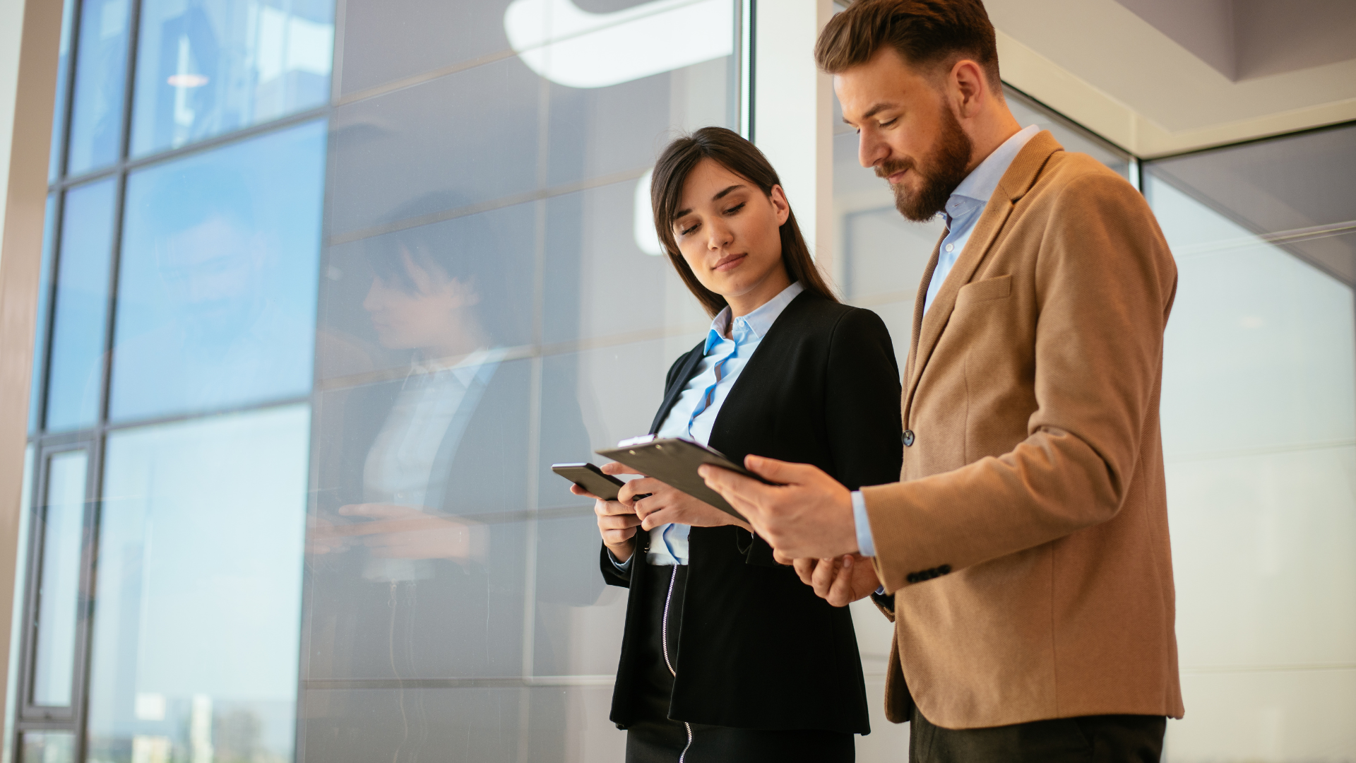 A man and a woman are looking at a tablet in an office.