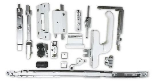 Varios componentes de hardware para ventanas de color blanco y plateado dispuestos sobre una superficie blanca.