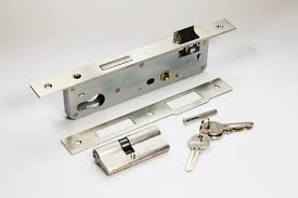 Mecanismo de cerradura de puerta plateada con llaves y placas sobre una superficie blanca.