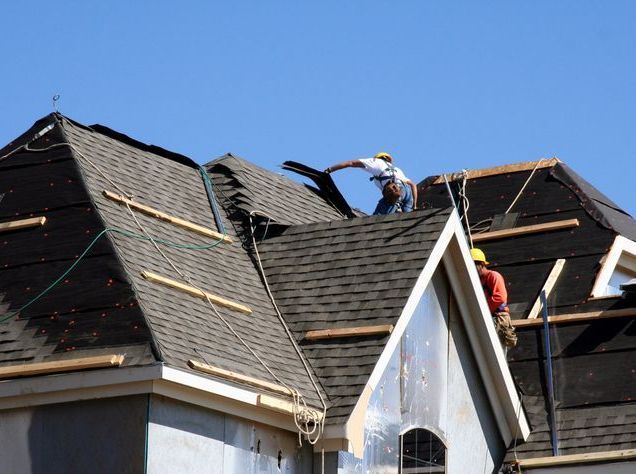 Roof Workers on top of house with blue sky