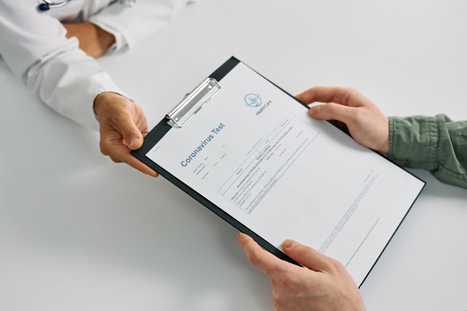 A person is handing a clipboard to a doctor.