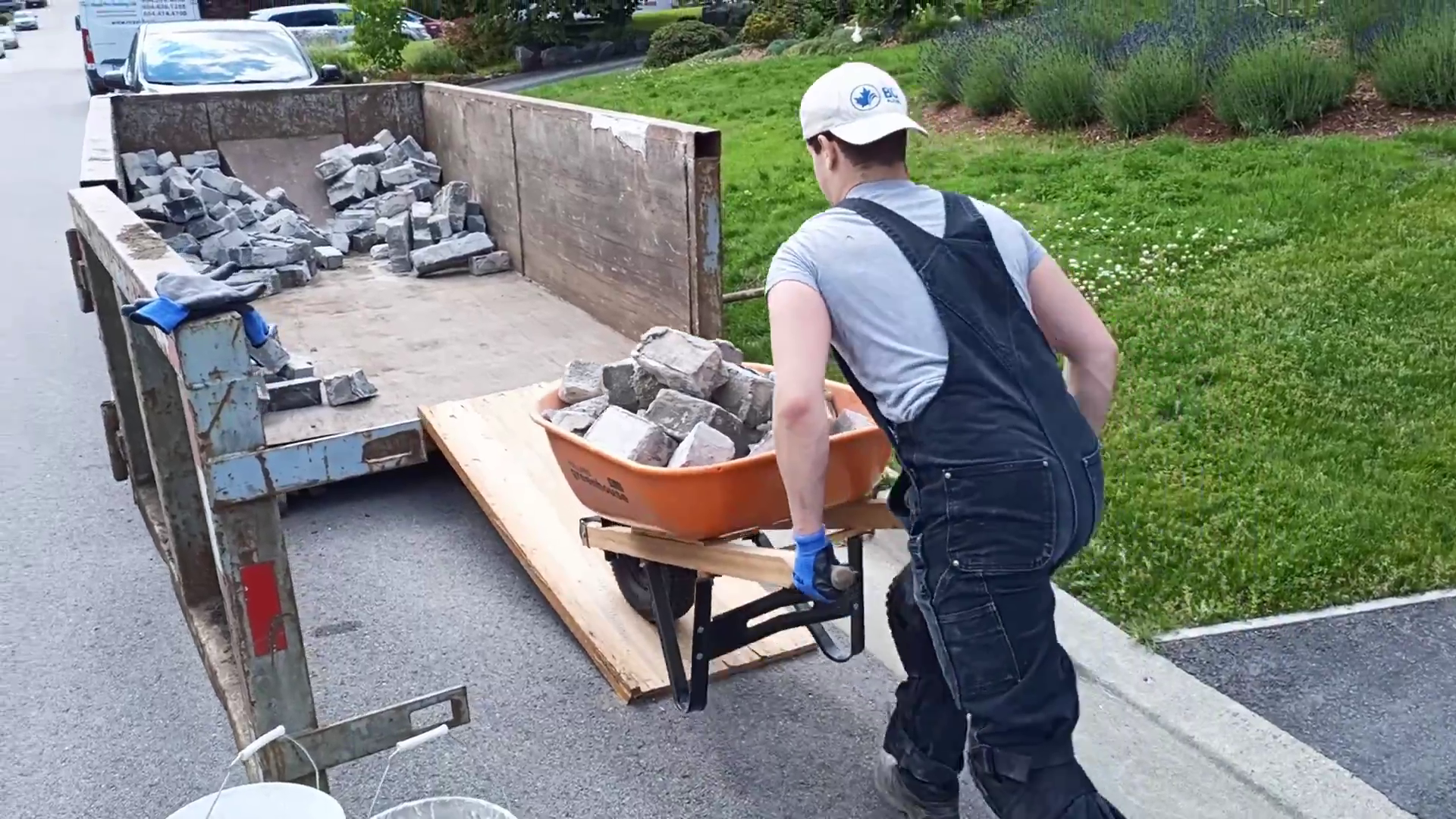 A masonry worker is wheelbarrowing blocks into a truckbed.