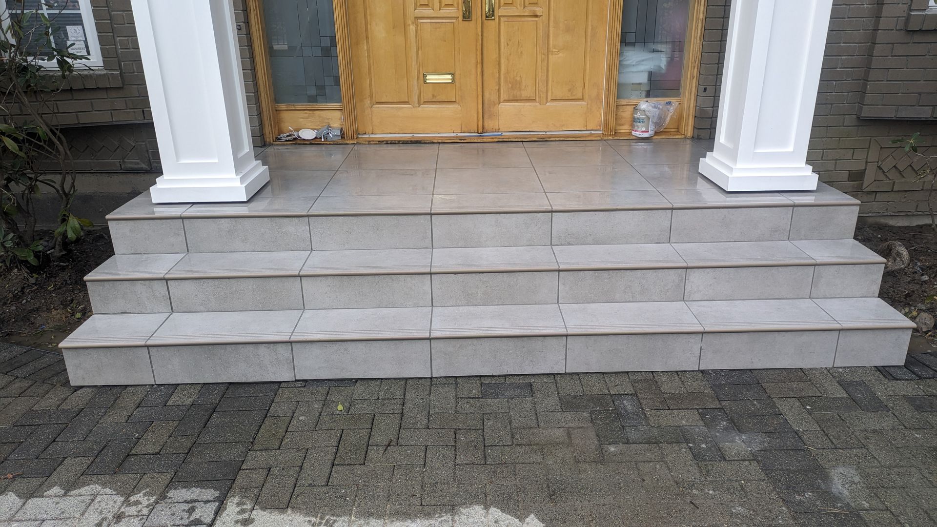 Natural stone steps and patio made from sleek and elegant stone tiles in front of a residential home