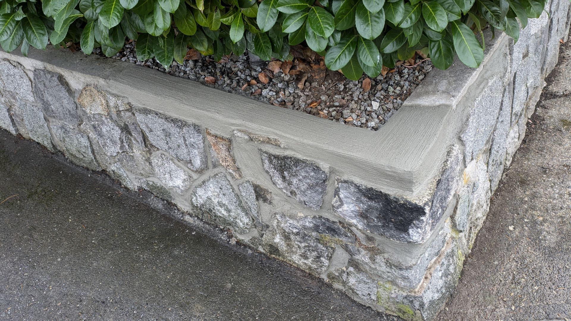Get concrete repairs done to make your old masonry look and function like new again. A small natural stone retaining wall repaired with fresh concrete