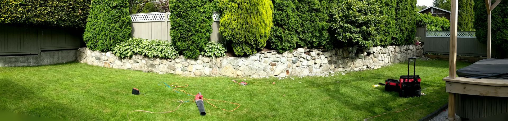 backyard retaining wall made from natural round stones set with mortar.