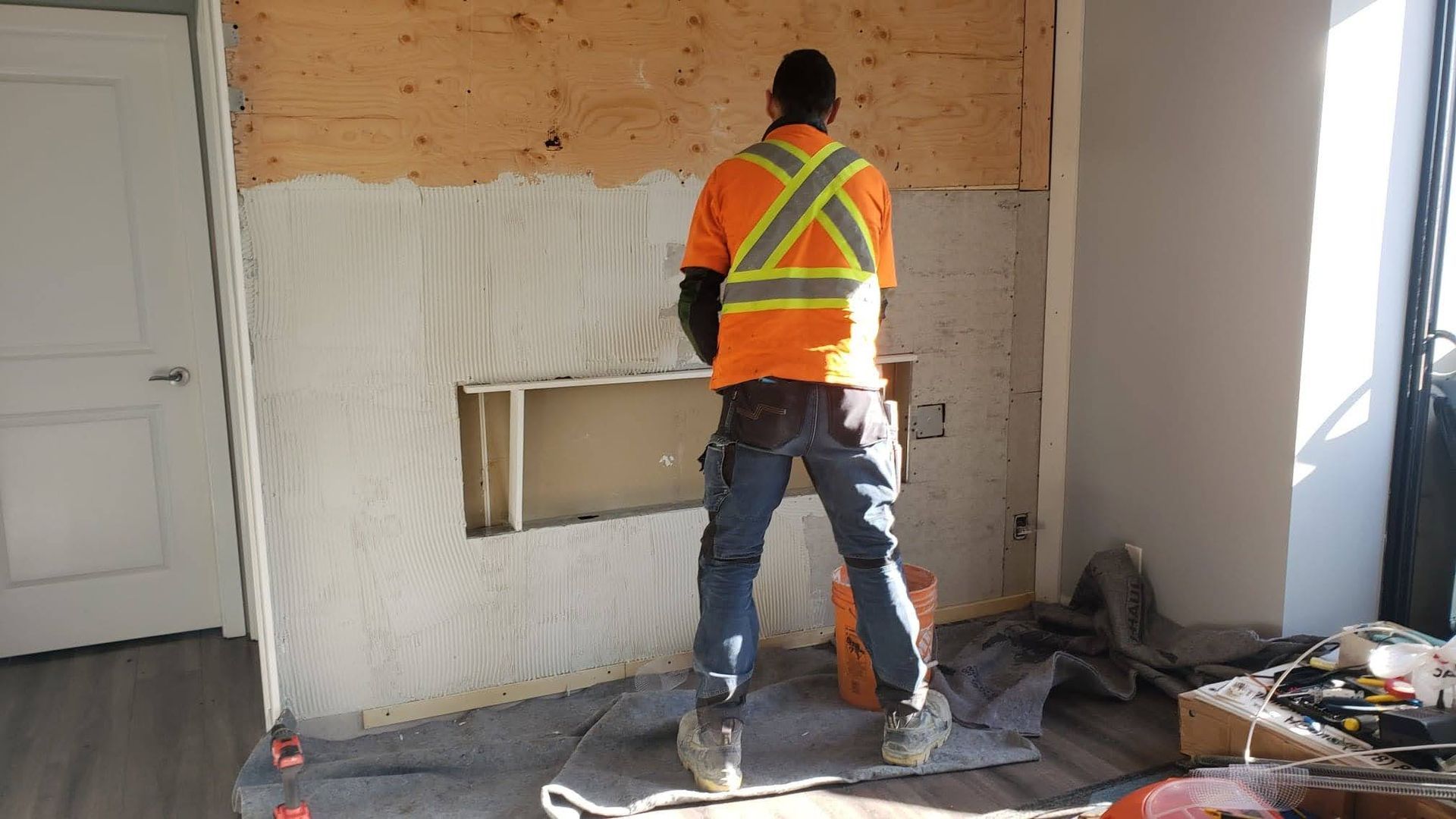 Chris adding grout to wall before installing stone veneer on modern fireplace.