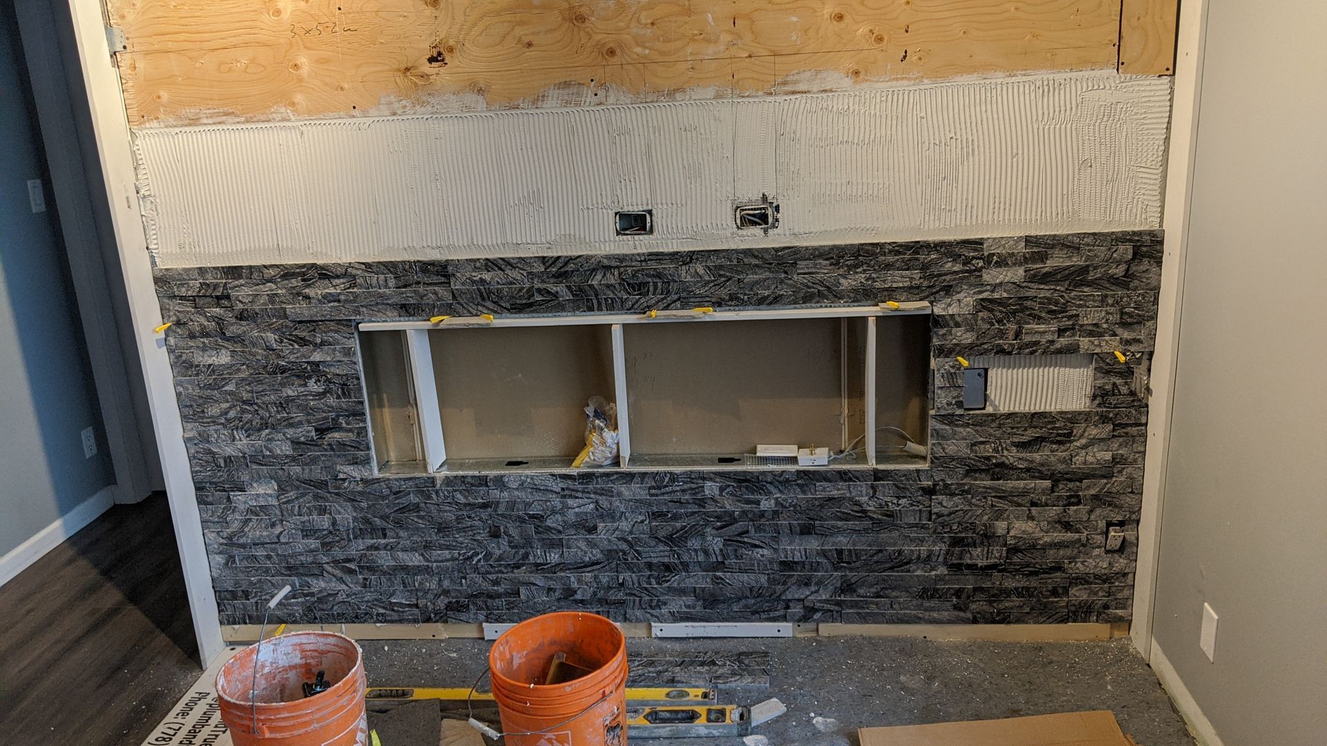 Modern fireplace with stone veneer installed halfway.
