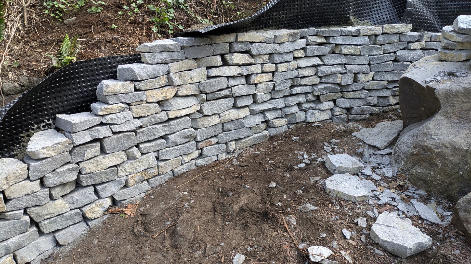 A stone wall is being built on top of a dirt hill.