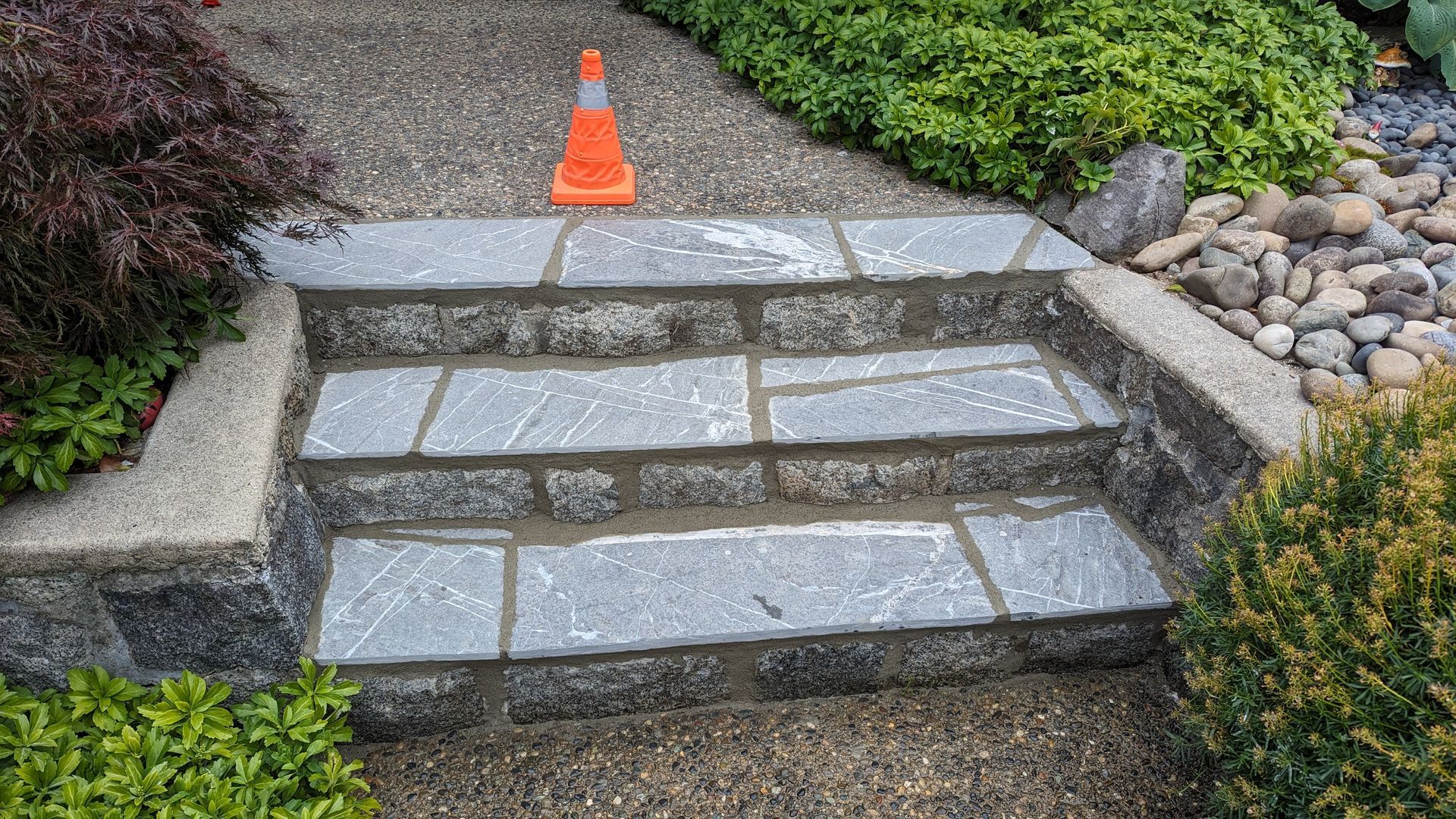 Three newly installed natural stone steps on the front pathway of a residential home