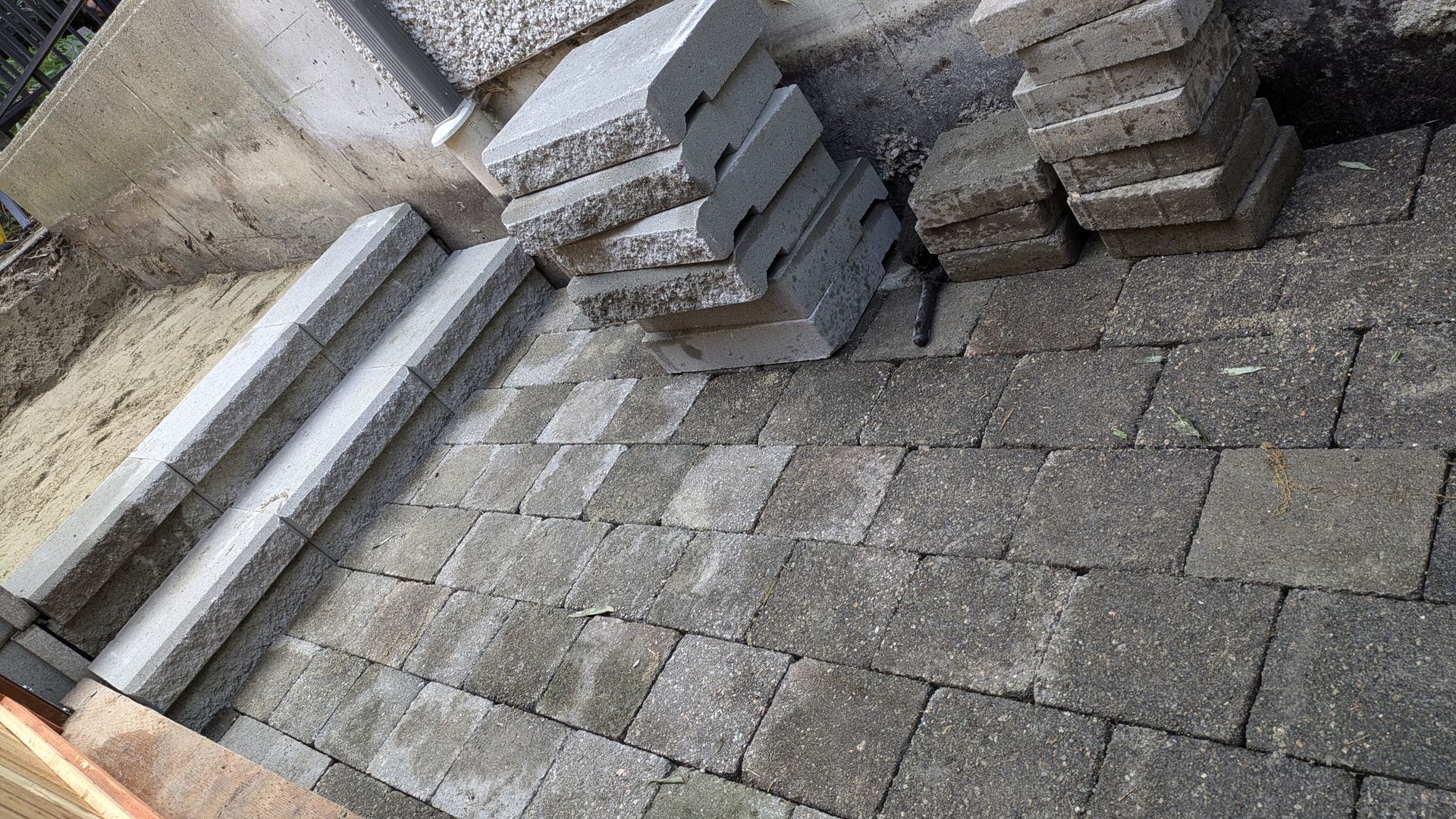 Paver stone walkway and concrete slab steps going around the back side of residential house