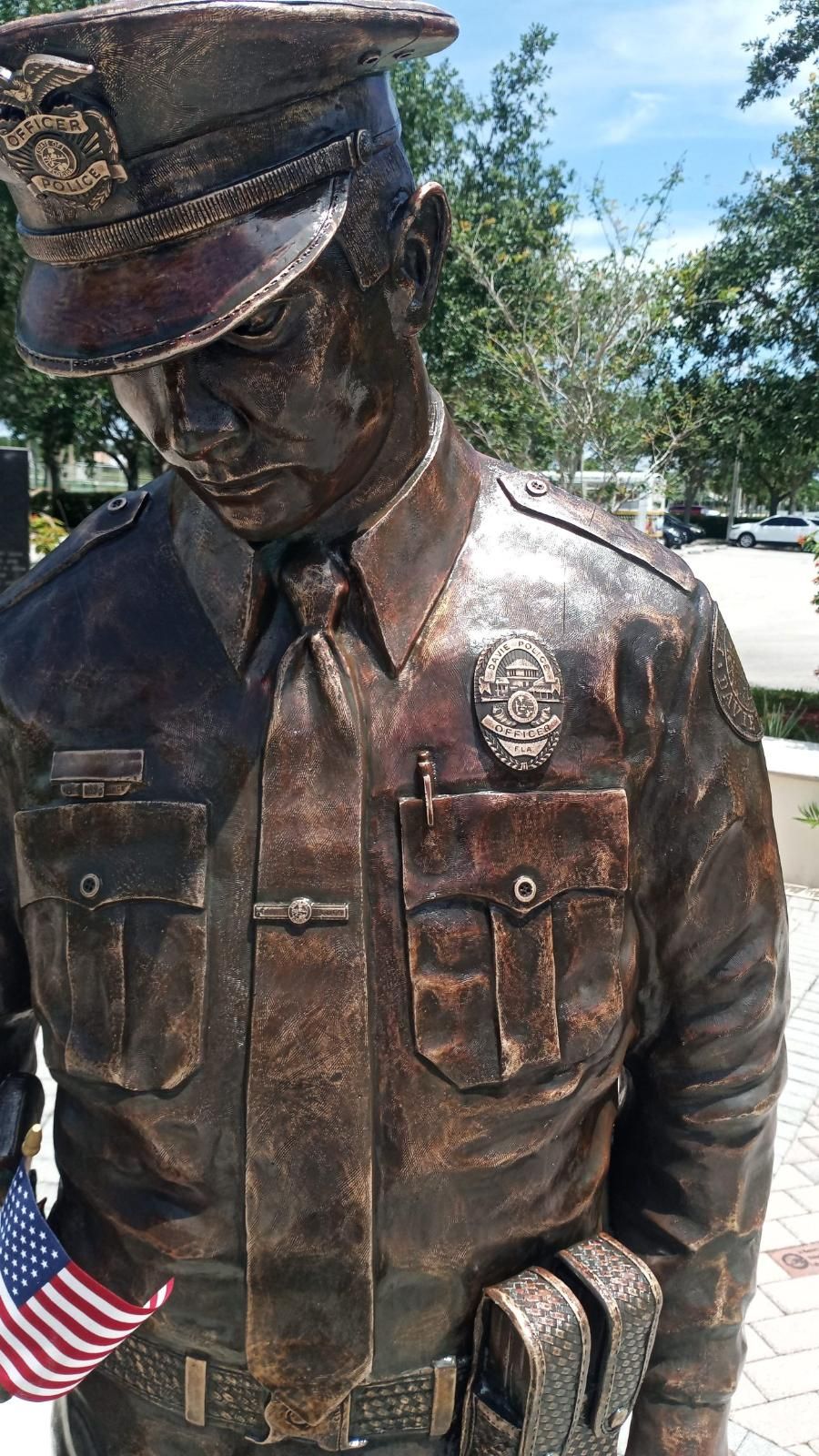 A bronze statue of a police officer holding an american flag.