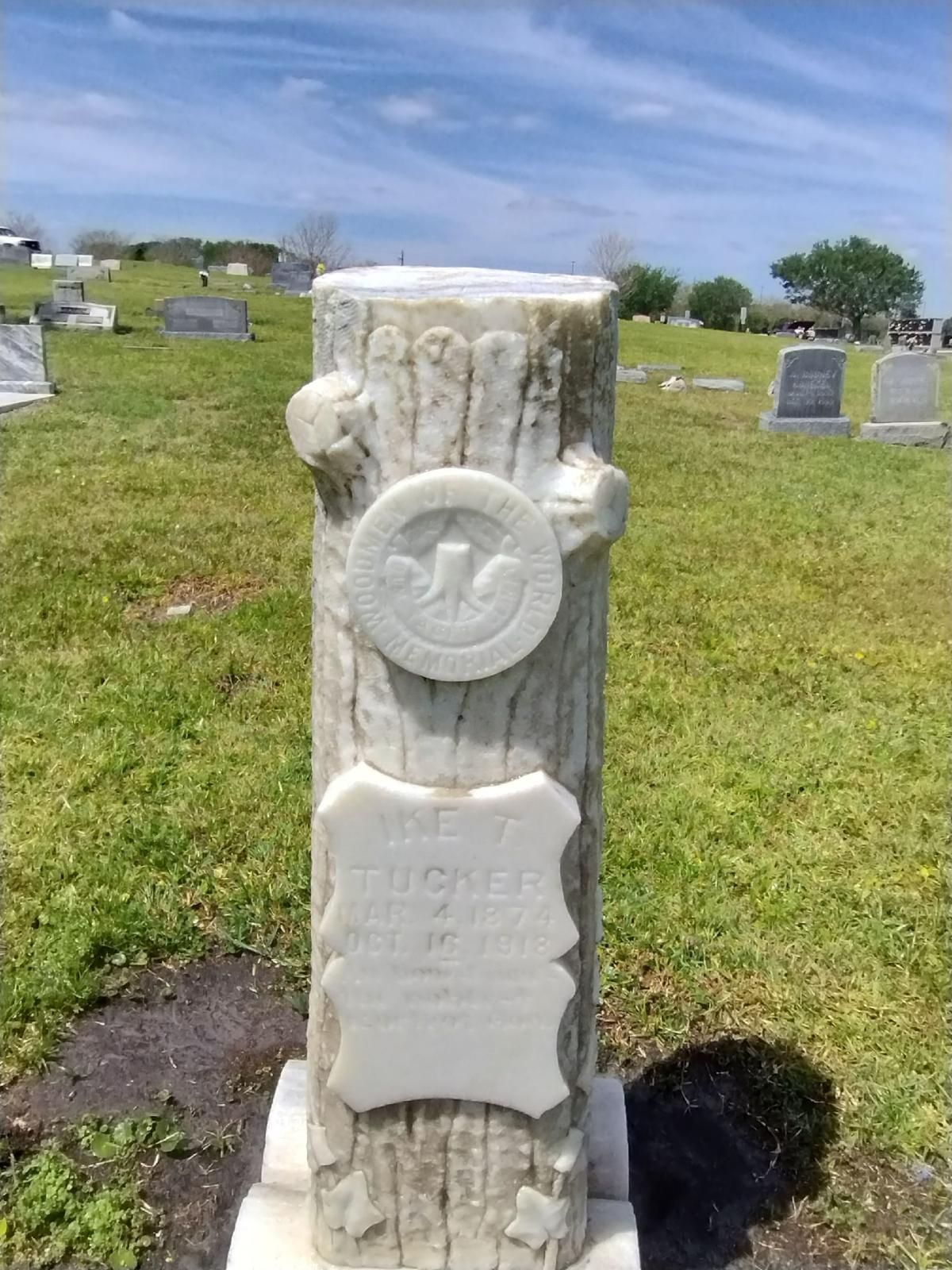 A gravestone in a cemetery that looks like a tree stump