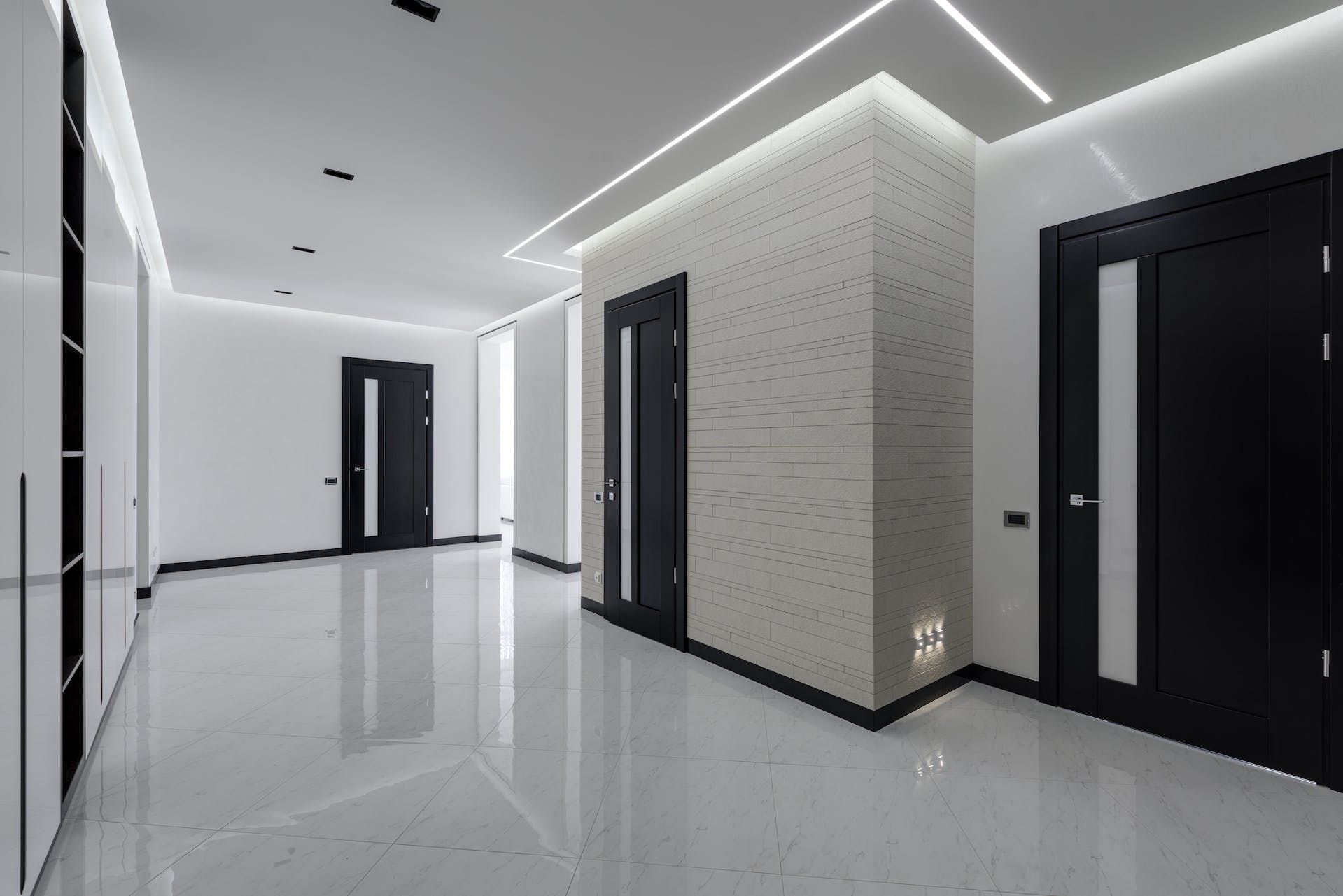 An empty hallway with black and white doors and a ceiling light.