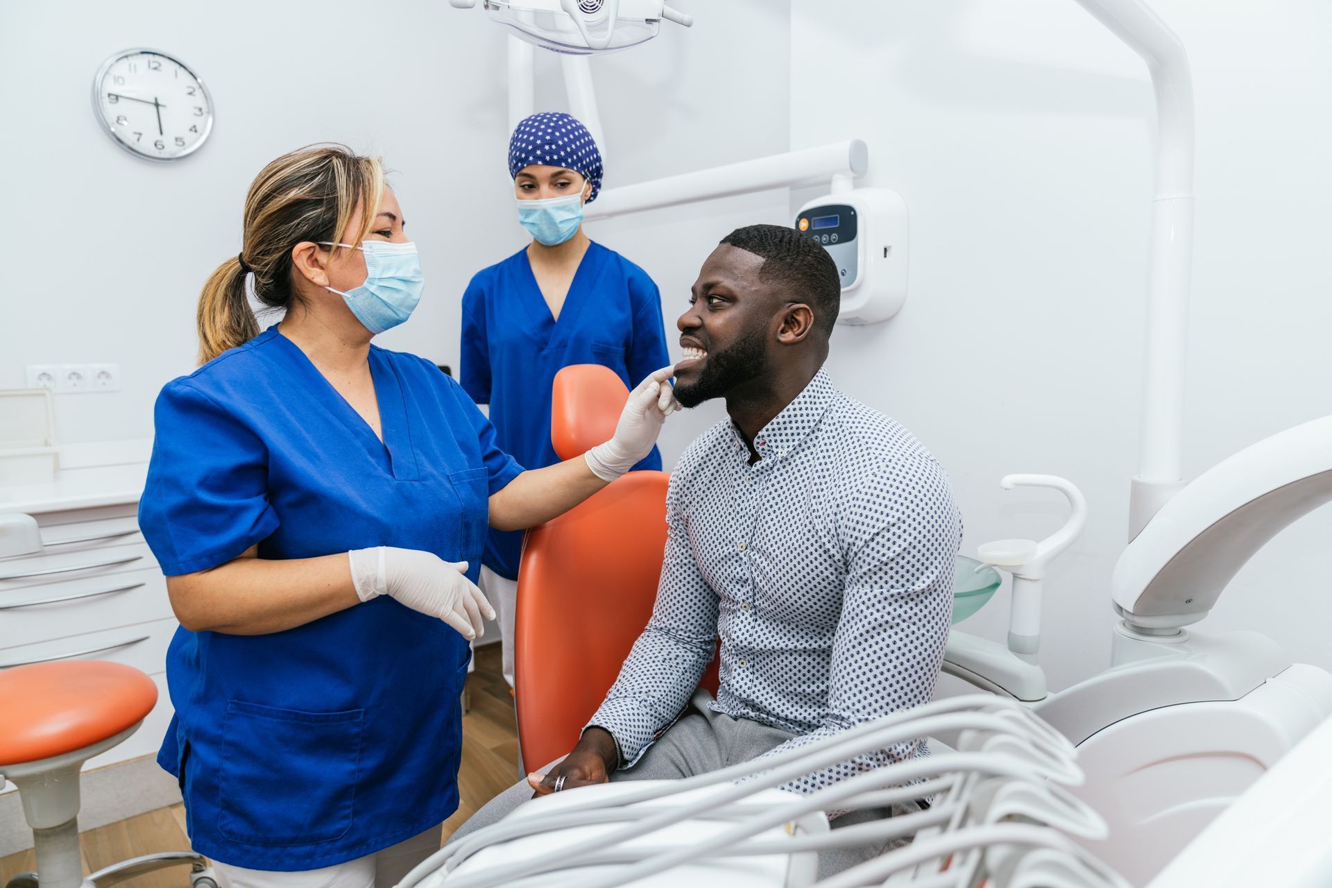Emergency dentists examining patient with dental pain in modern clinic with assistant nearby.