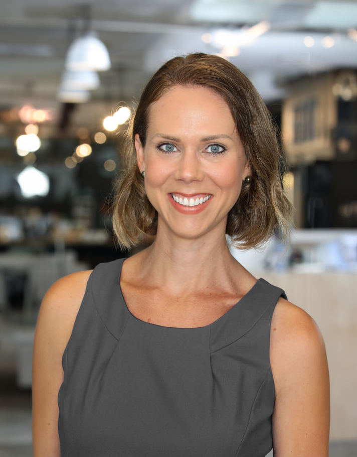 A woman in a grey dress is smiling for the camera