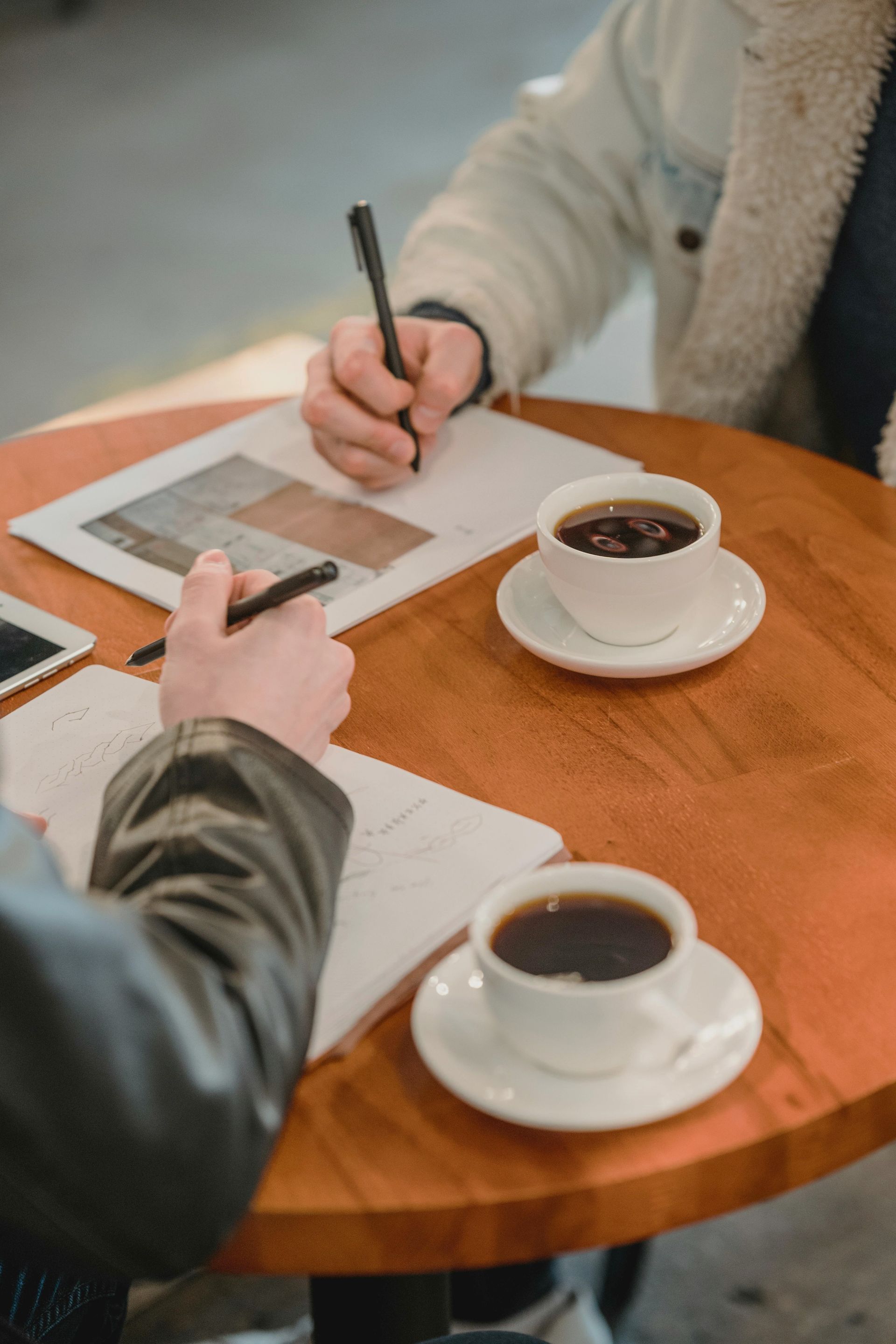 Two people are sitting at a table with cups of coffee.