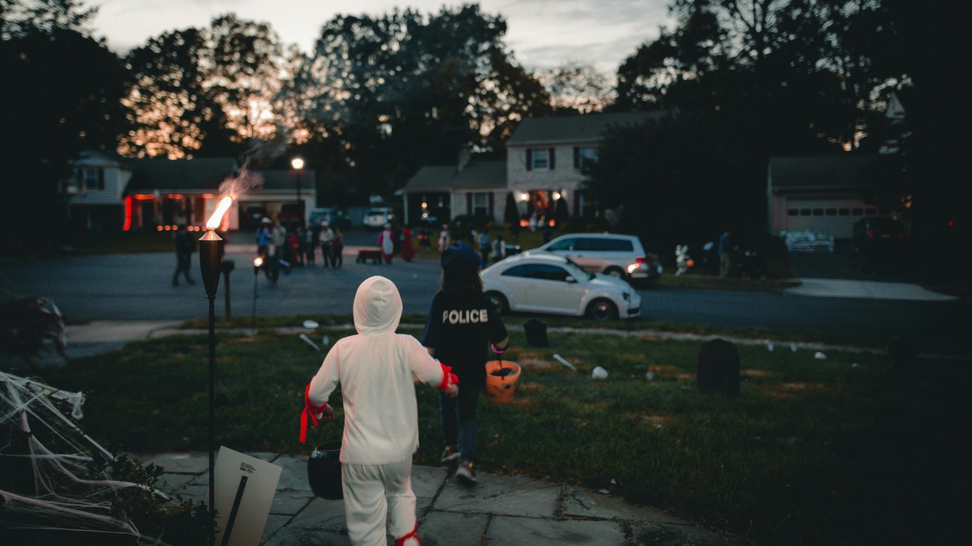 A little girl in a costume is walking down a sidewalk with a police officer.