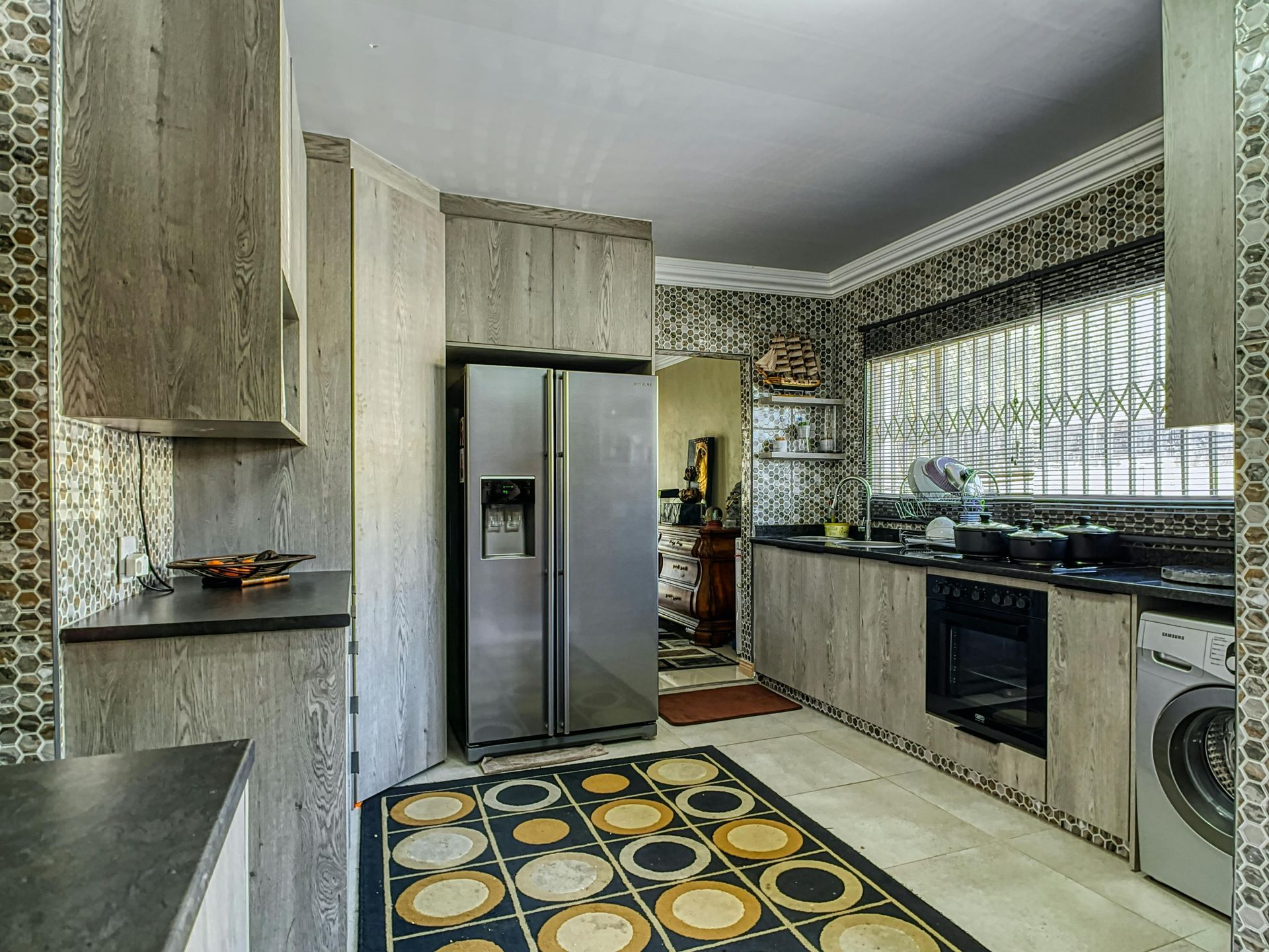 A kitchen with a stainless steel refrigerator and a rug on the floor.