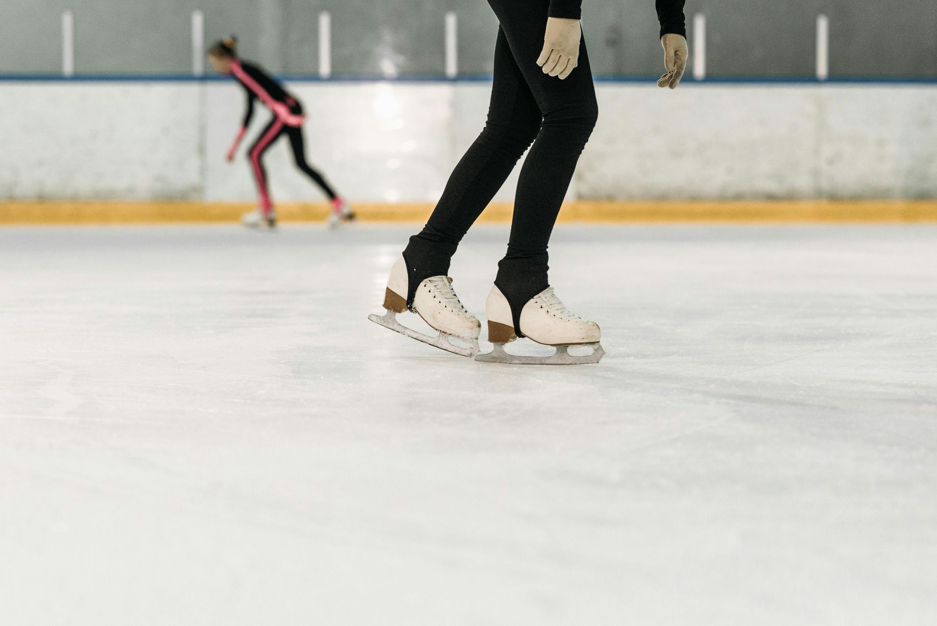 A woman is ice skating on an indoor rink.