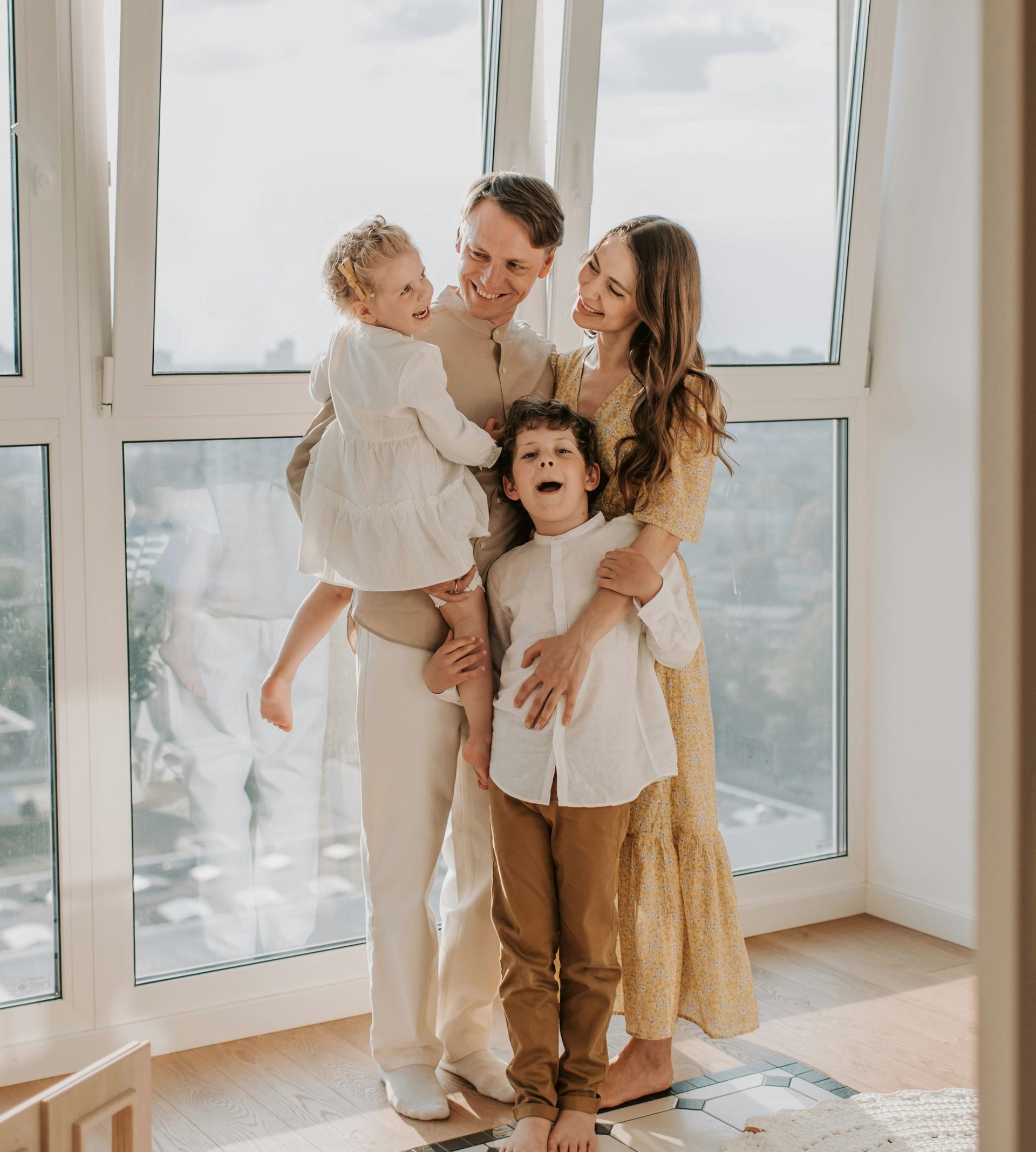 A family is posing for a picture in front of a window.