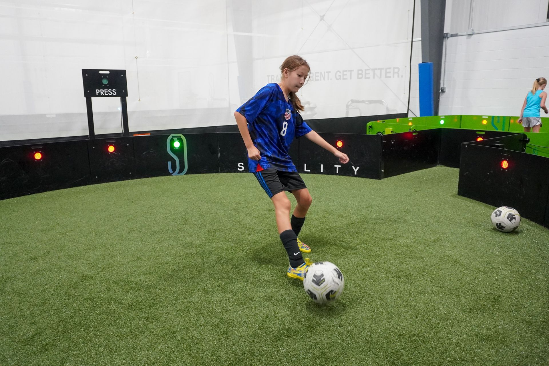 A girl is kicking a soccer ball on a field.