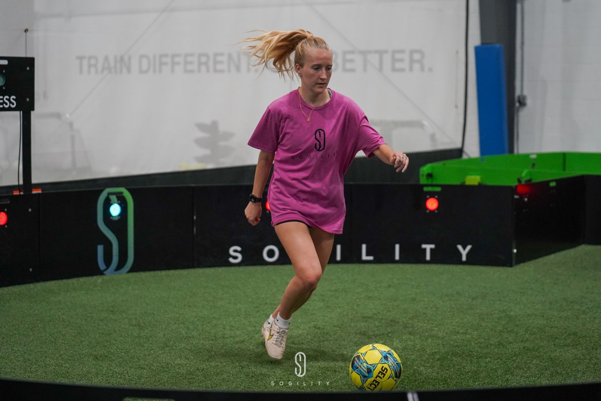 A young girl is kicking a soccer ball on a field.