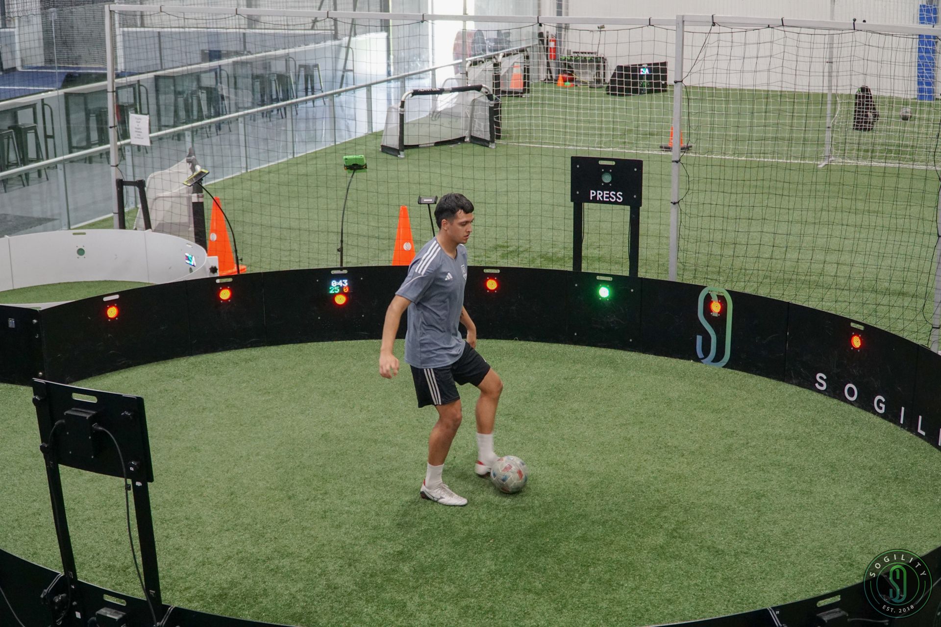 A man is kicking a soccer ball in a circle on a field.