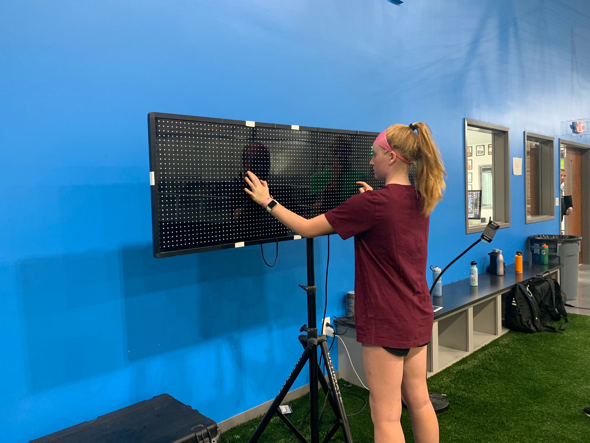 A woman is standing in front of a large screen in a gym.