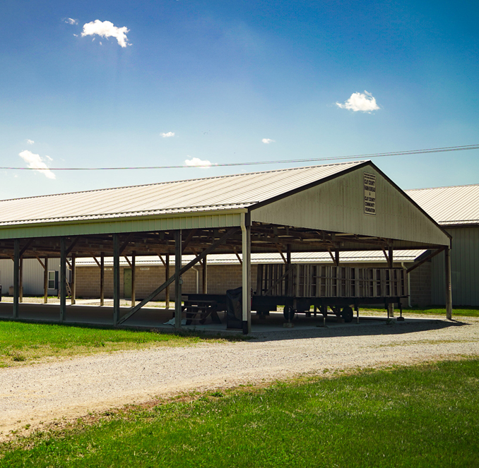 Plain building entrance with green awning, white metal siding, and gravel lot under a blue sky