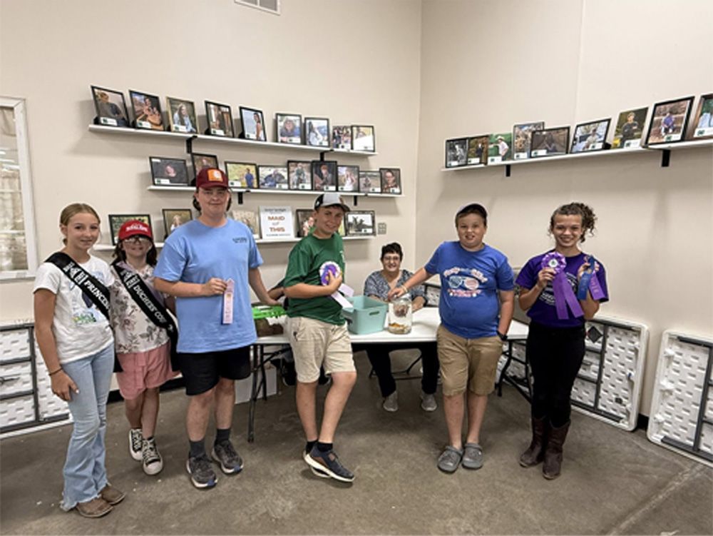Group of people posing in a store aisle beside shelves of photos and small display items