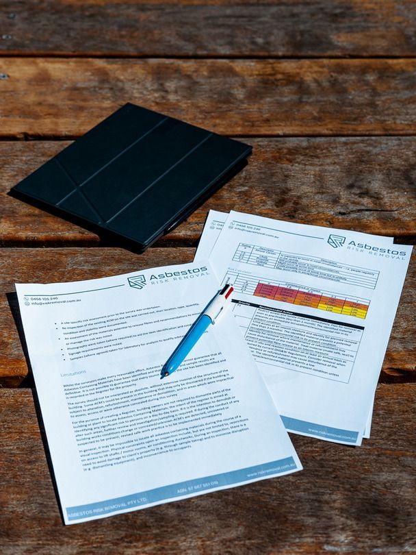 A Person in An Orange Jacket Is Writing on A Clipboard — Asbestos Risk Removal In Rockhampton, QLD