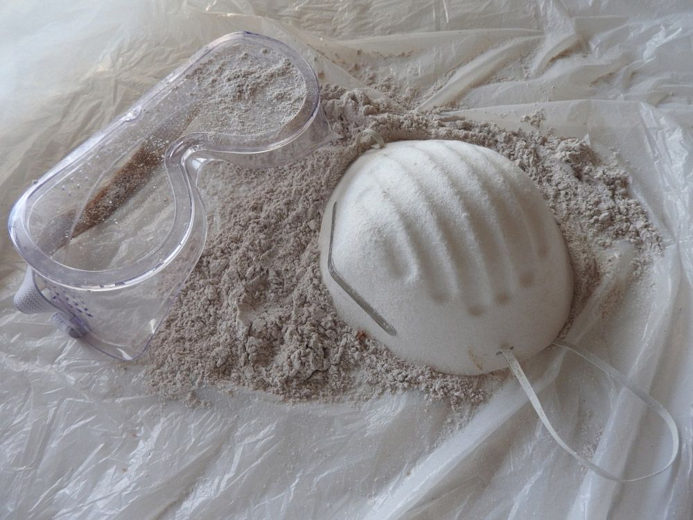 A Mask and Goggles Are Sitting on Top of A Pile of Sand — Asbestos Risk Removal In Mackay, QLD
