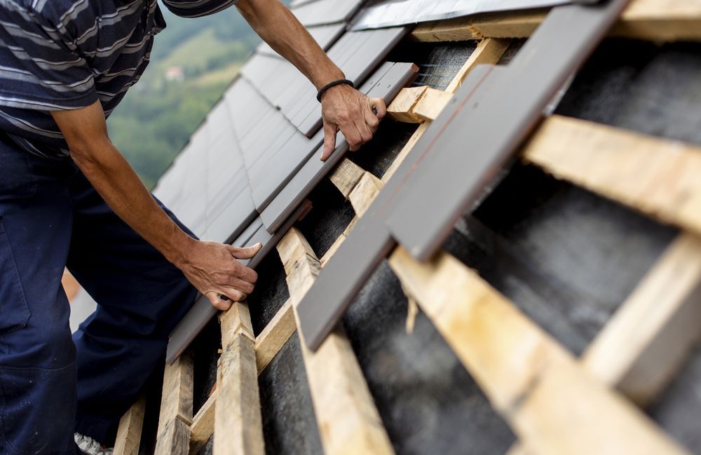 A Man Is Working On The Roof Of A House — Asbestos Risk Removal In Capricorn Coast, QLD