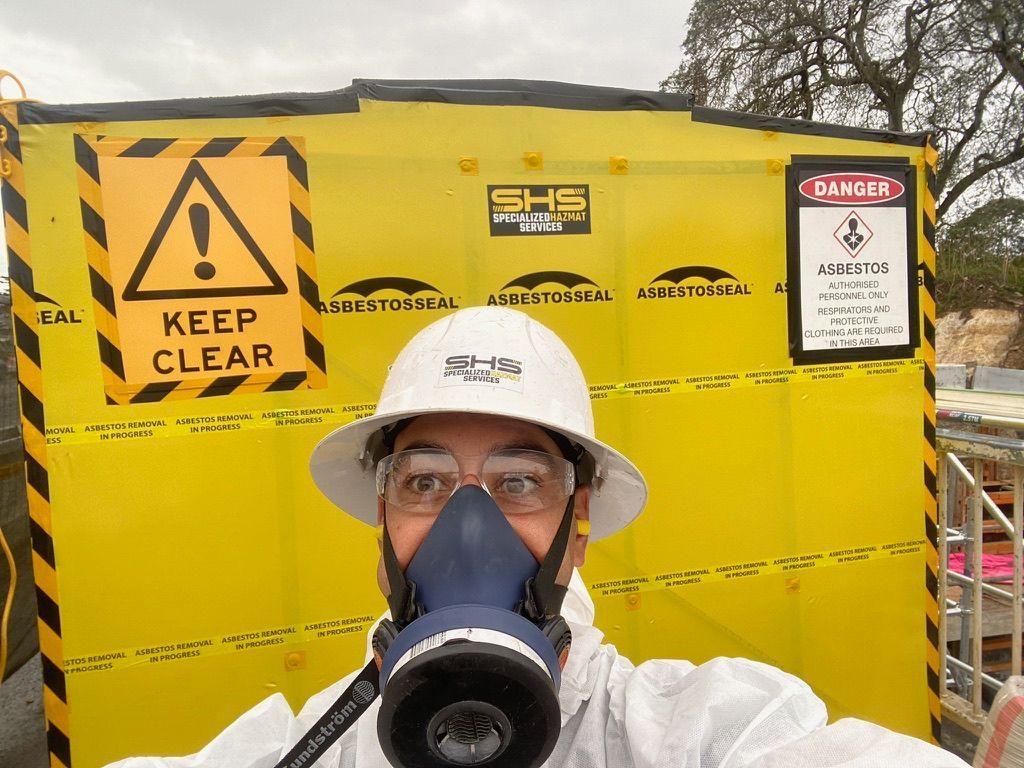 A Man in A White Suit Is Standing on Top of A Roof — Asbestos Risk Removal In Rockhampton, QLD