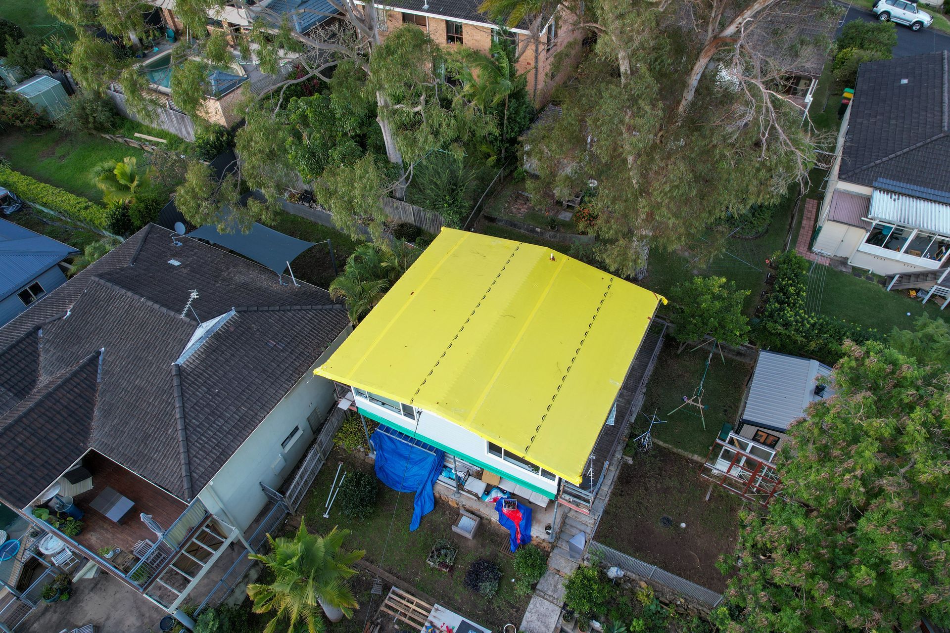 Two Men In White Overalls Are Standing On Wooden Boards Holding A Piece Of Asbestos — Asbestos Risk Removal In Gladstone, QLD