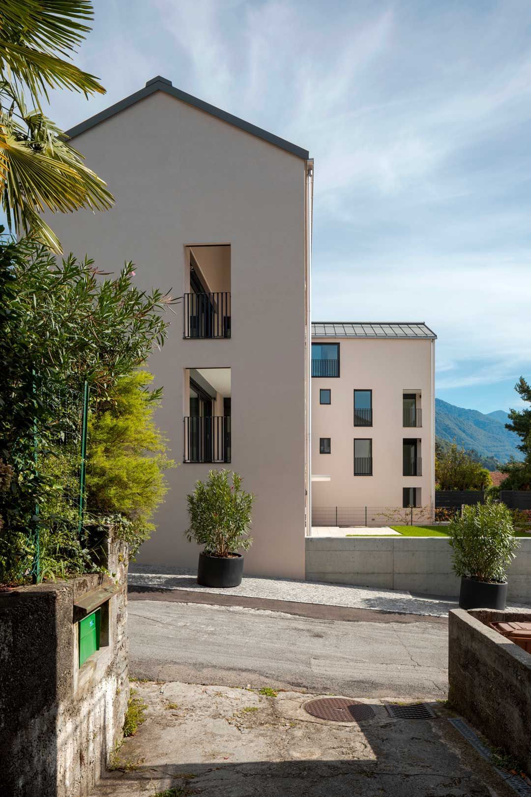 Un grande edificio bianco con balcone è circondato da alberi e cespugli.