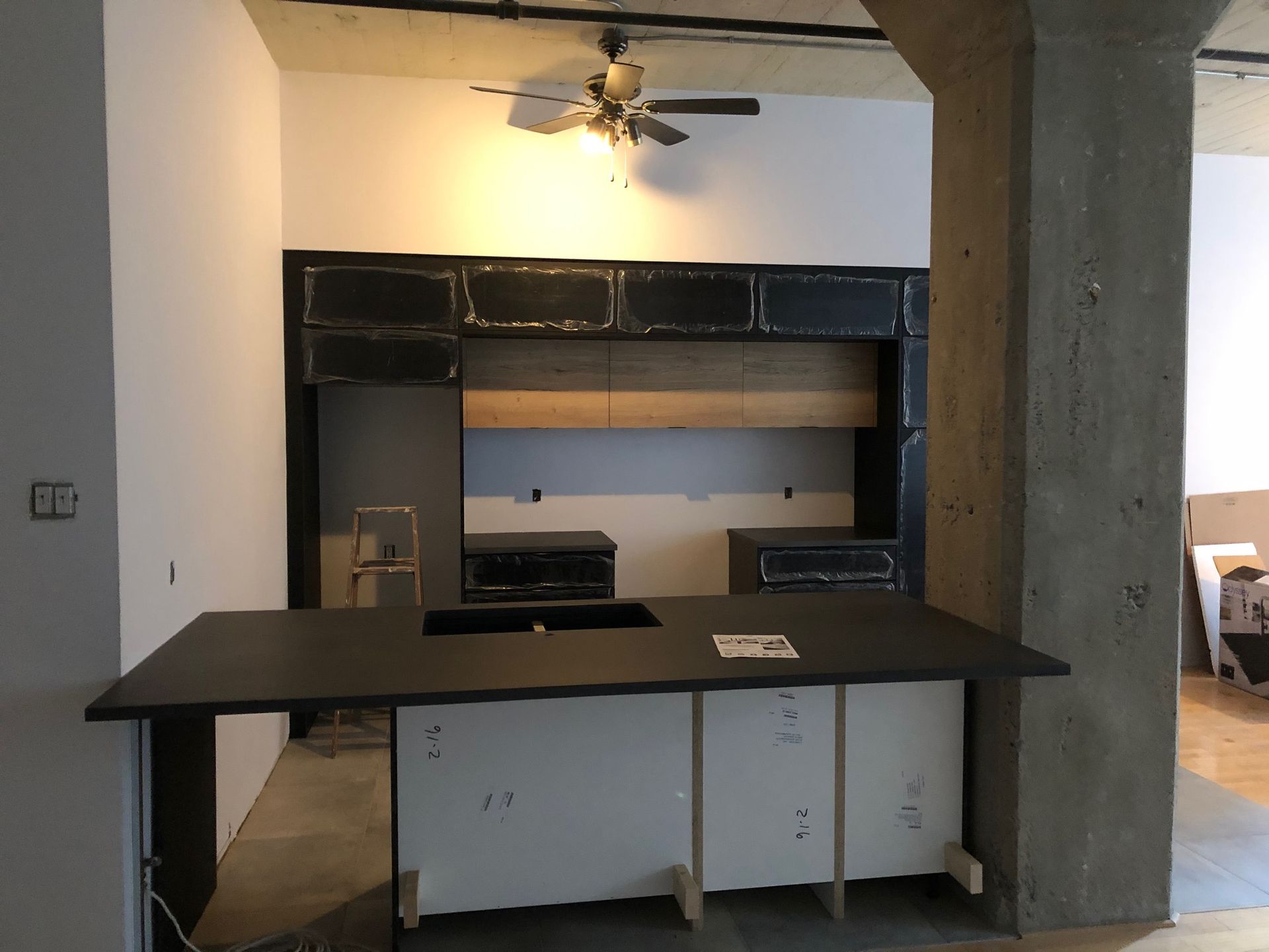 Îlot de cuisine et armoires dans un espace industriel rénové, avec comptoirs et armoires foncés.