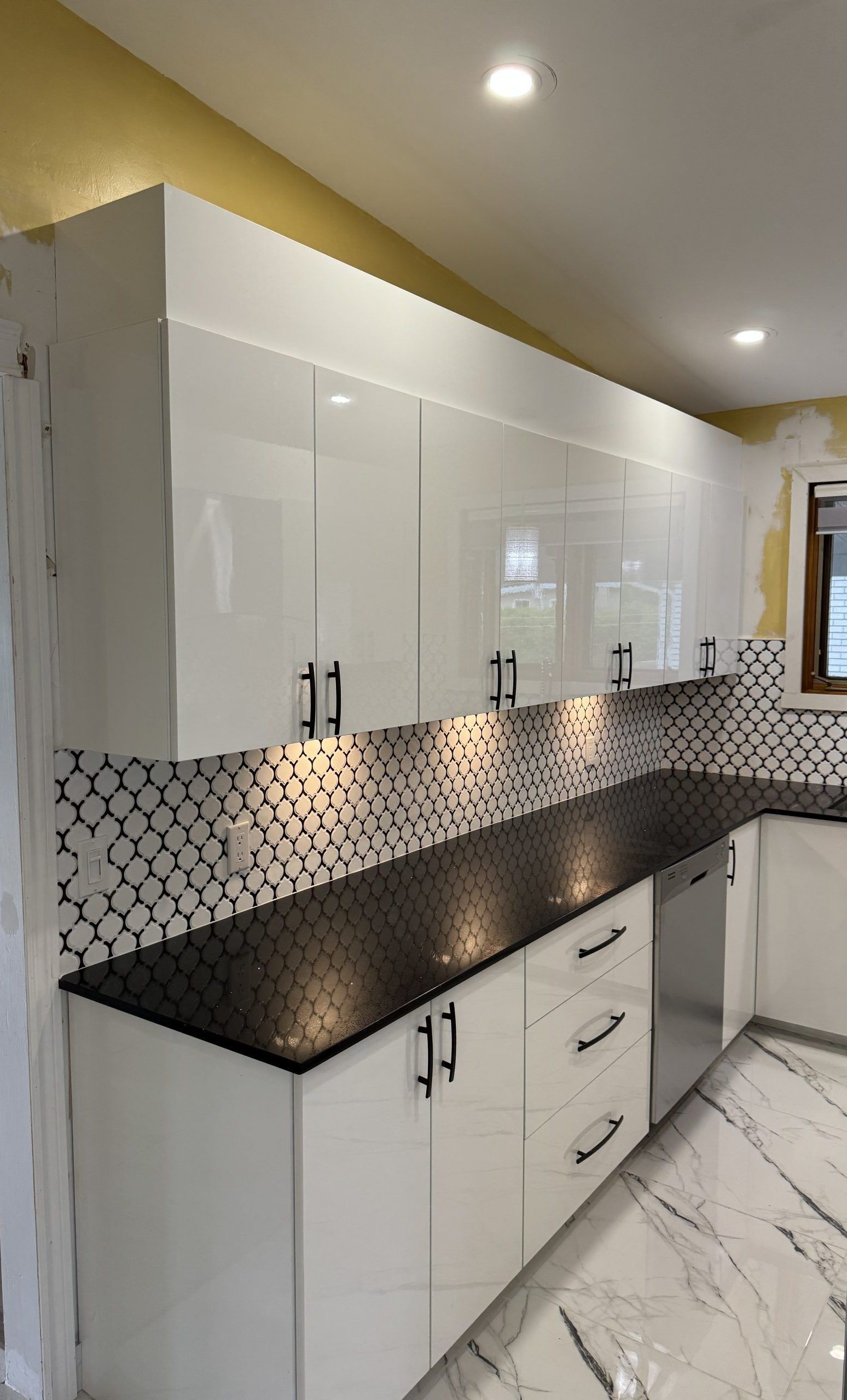 Cuisine blanche moderne avec comptoirs et dosseret noirs.