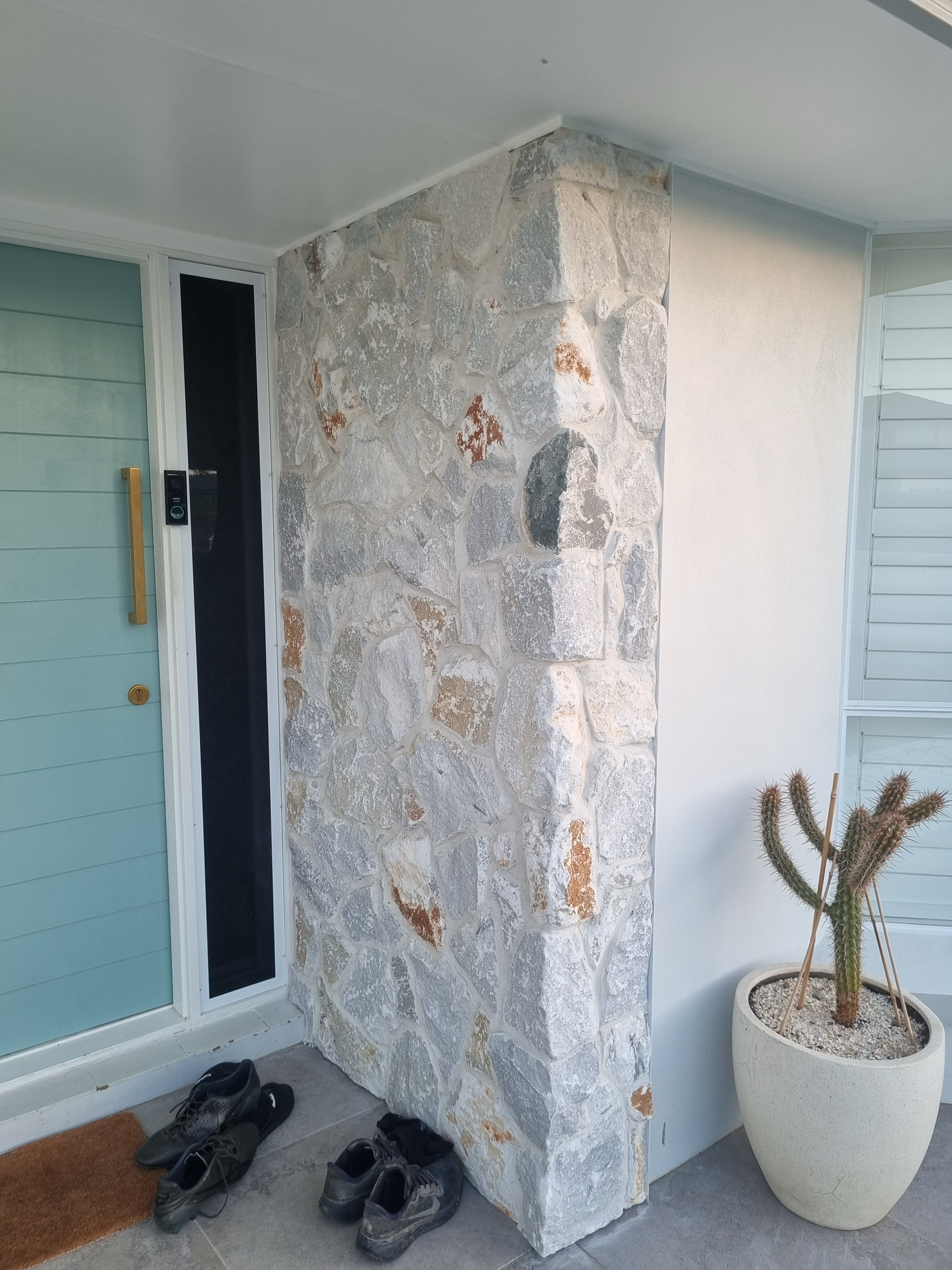 Front porch with white stone column, light blue doors, shoes, and a potted cactus plant — Coastline Earthworks in Helensvale, QLD