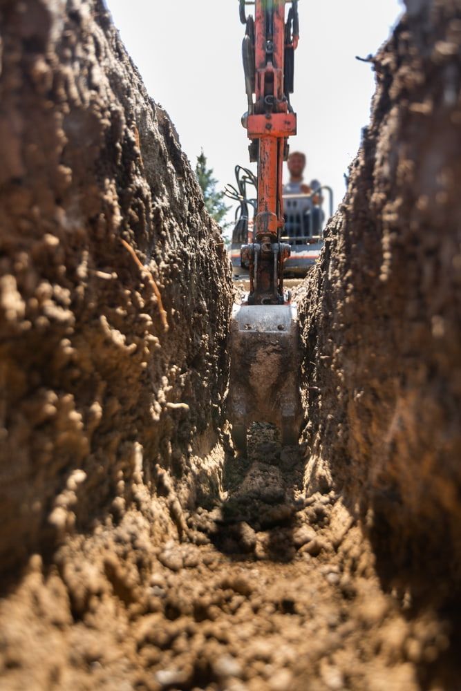 An excavator digs a trench in the earth on a sunny day. — Coastline Earthworks in Helensvale, QLD