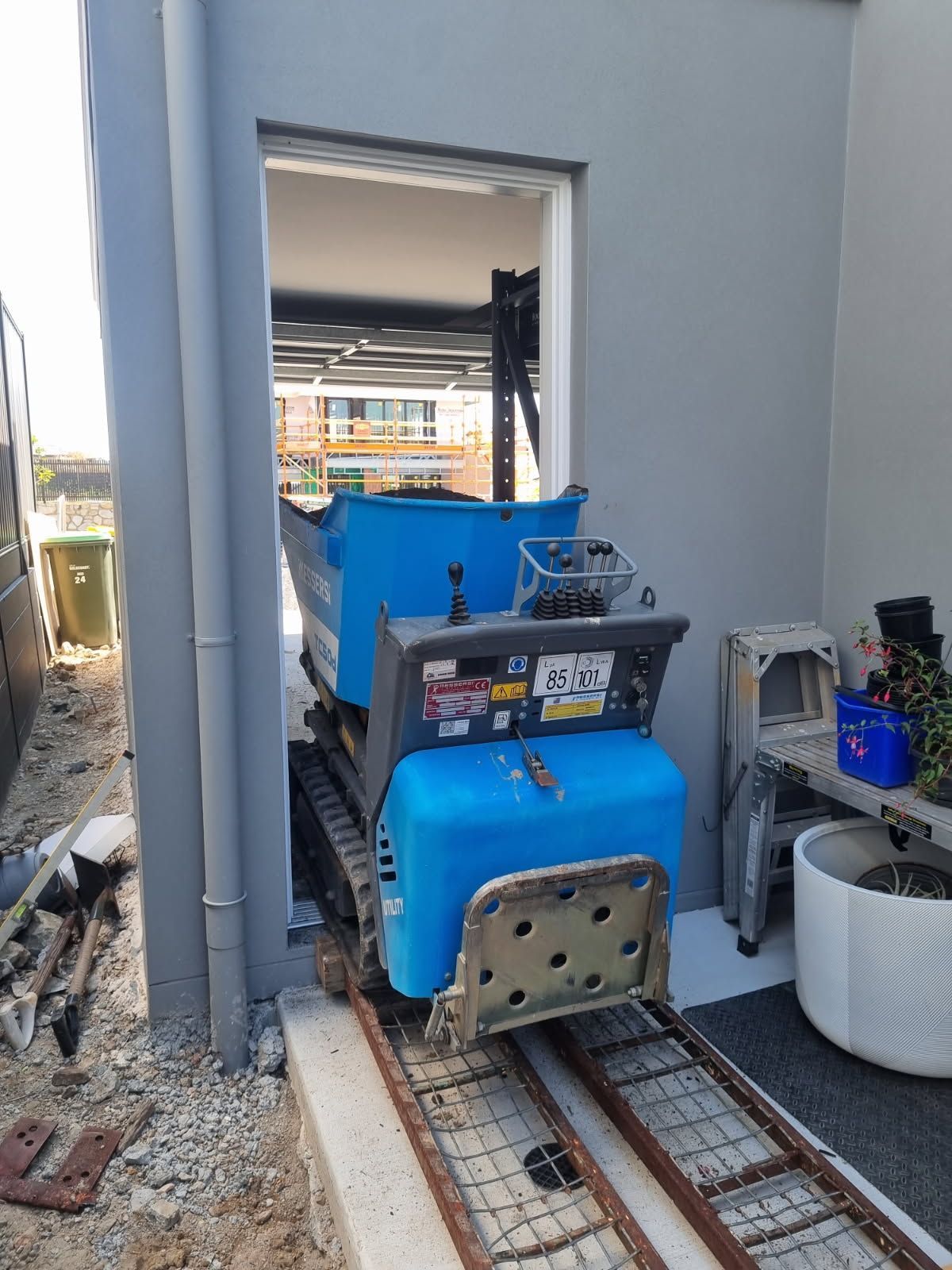 Blue mini-dumper on tracks exiting a doorway, construction site. — Coastline Earthworks in Helensvale, QLD