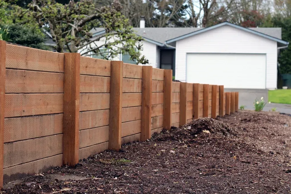 Wooden fence in front of a white house with a garage, built in a residential yard. — Coastline Earthworks in Brisbane, QLD