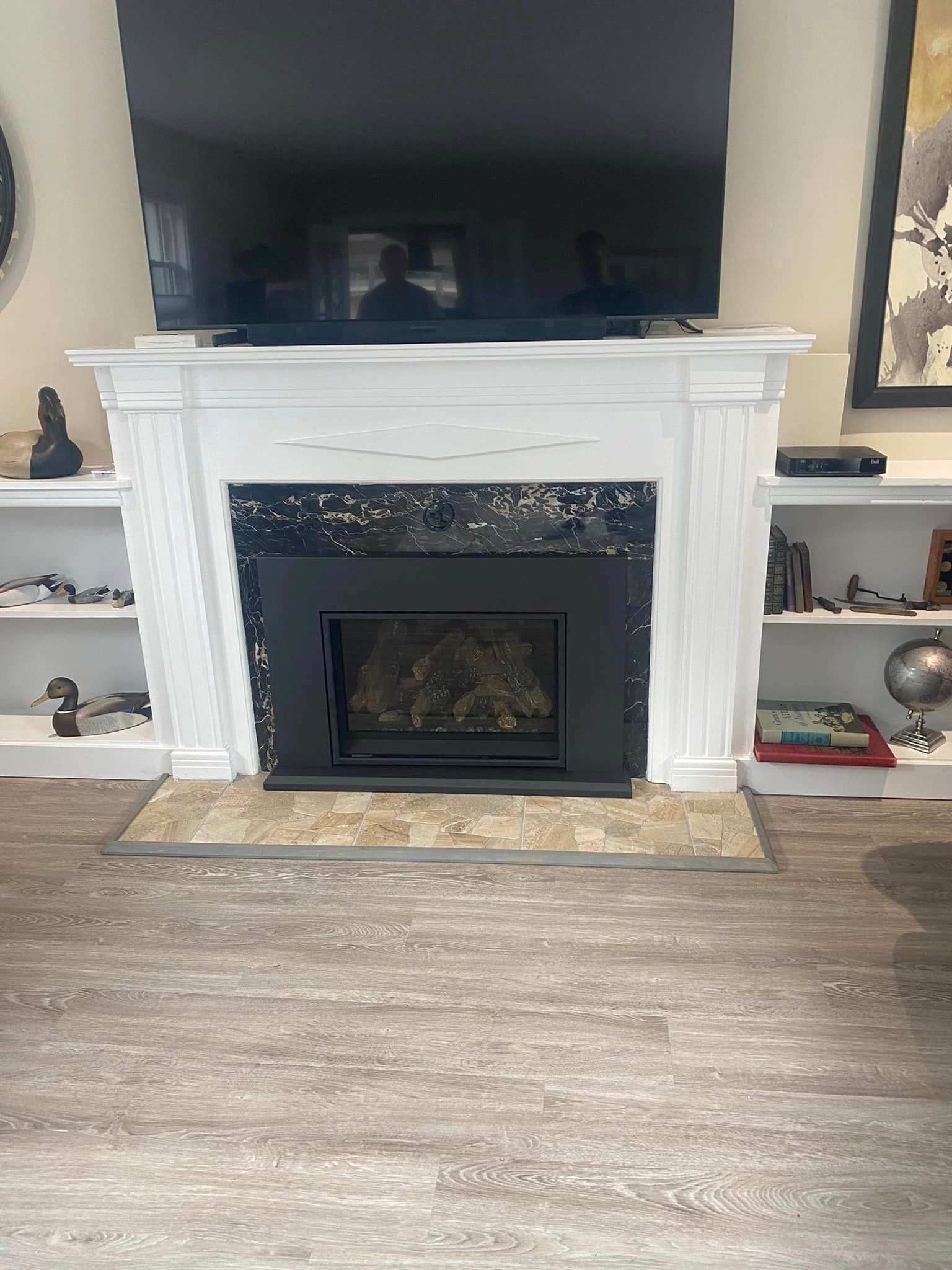 Fireplace with black insert, white mantel, and large TV above. Bookshelves on either side.