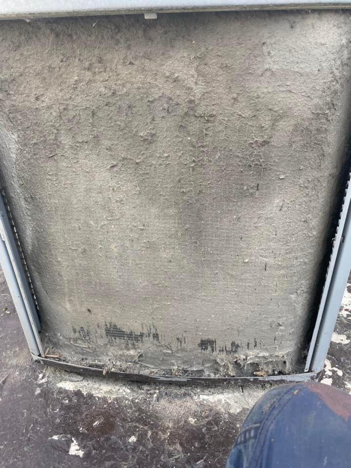 Dirty air filter, covered in grey dust and debris, set in a metal frame.