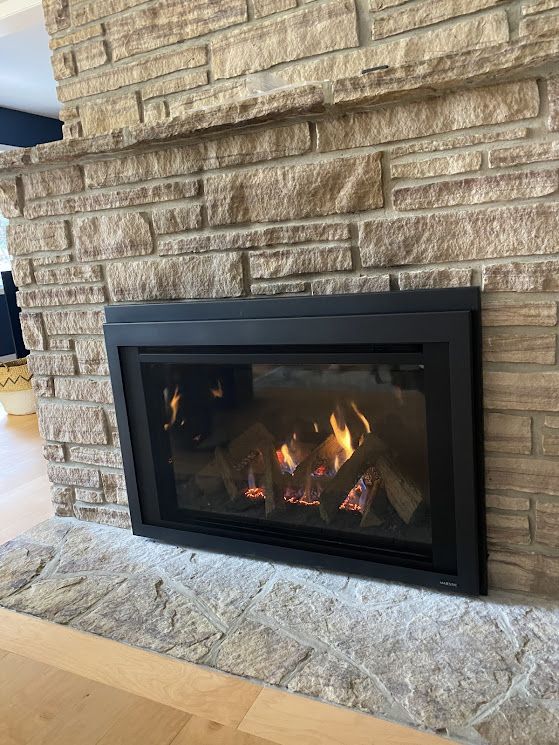 Gas fireplace with flames in a stone-faced surround.