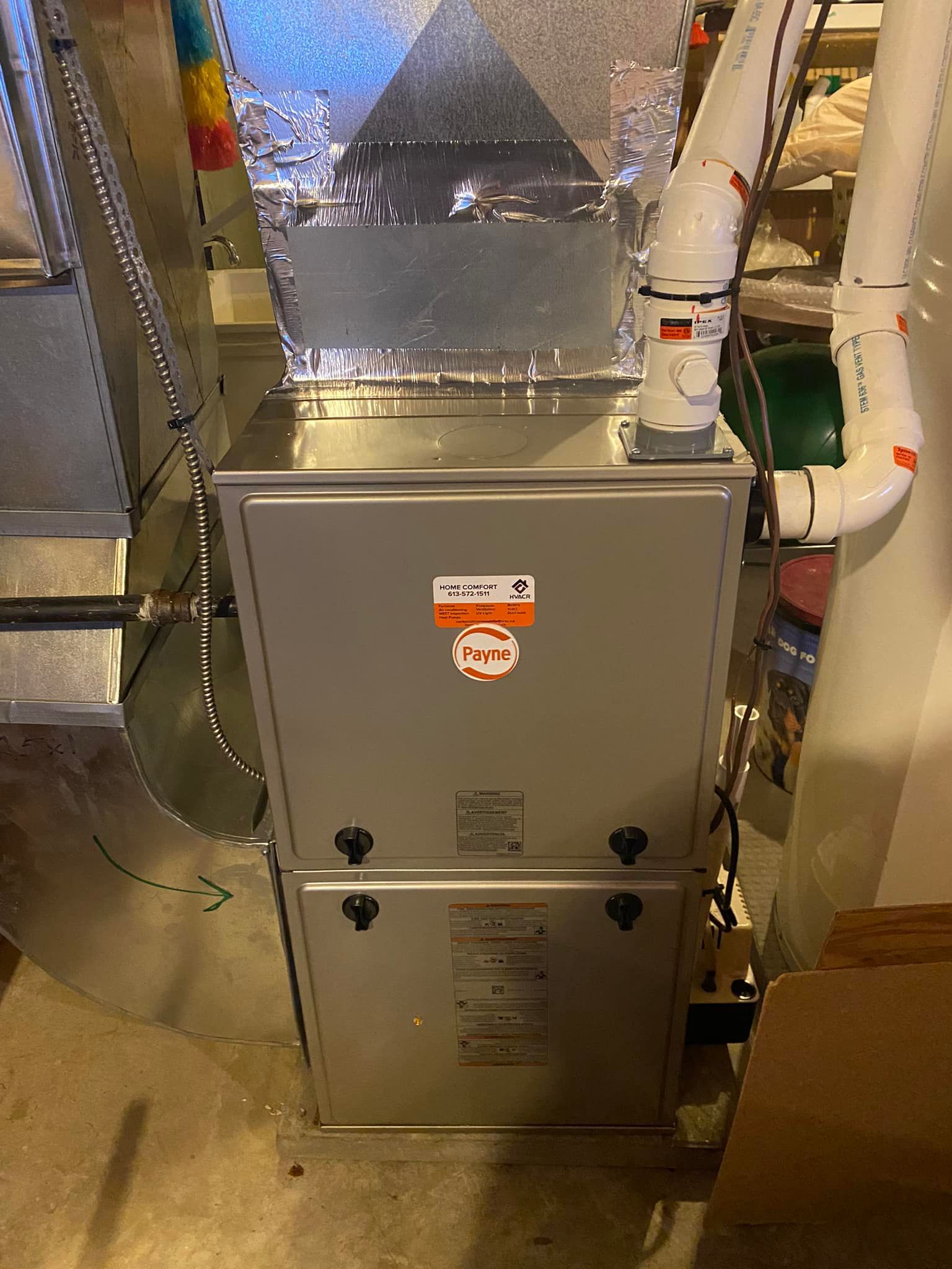 A furnace unit with ductwork and a vent in a basement setting.